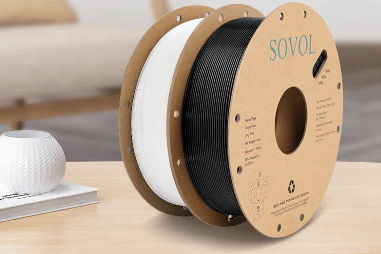 Sovol 3D printer filament spools in black and white on a wooden table indoors