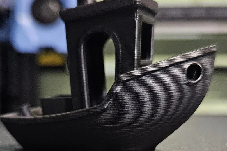 Black 3D printed boat model on a table, showcasing detailed layer lines