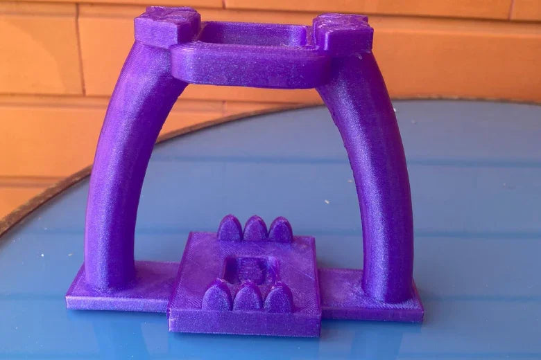 Purple 3D printed arch structure on a blue surface with orange brick background
