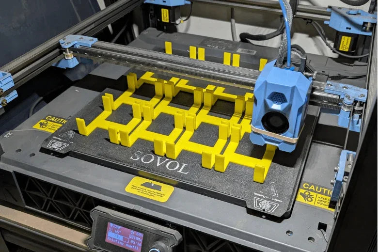 Sovol 3D printer creating yellow plastic parts on a print bed