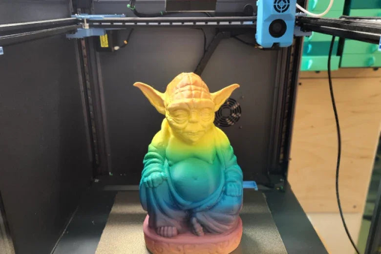 Colorful 3D printed Yoda Buddha statue inside a 3D printer