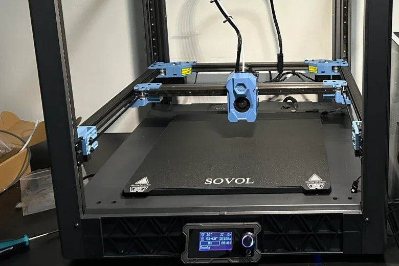 Sovol 3D printer with blue accents on a black table, close-up view of print bed and control panel